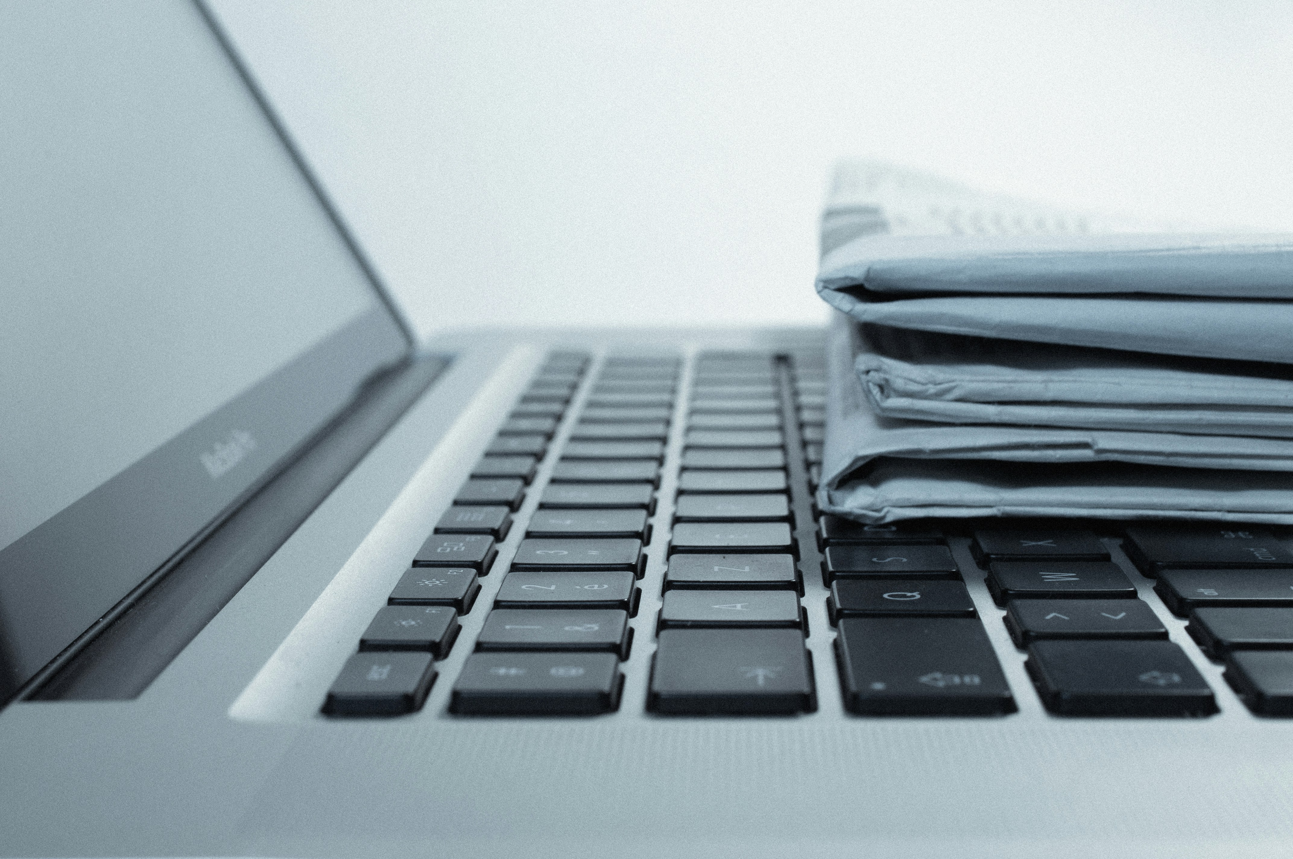 A laptop with a stack of papers resting on top, indicating a workspace or study area